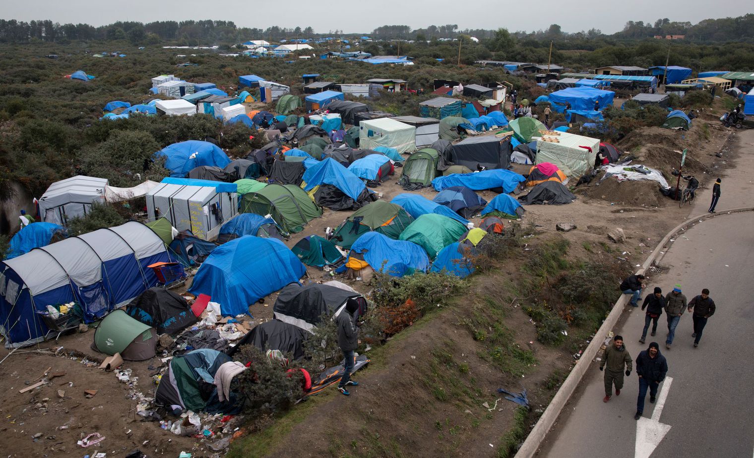 jungle-de-calais-migrants-migrants-walk-past-tents-in-the-new-jungle-make-shift-camp-in-calais_5461950.jpg