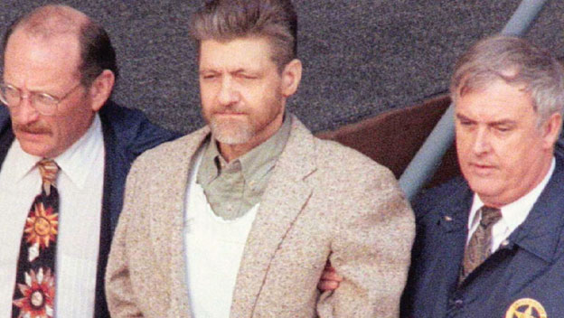 Ted Kaczynski, l'Unabomber, au centre de l'image entouré de 2 fédéraux.