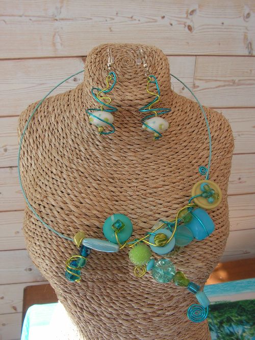 n°105:  parure sur cable turquoise en fil alu turquoise et anis, perles assorties en verre, boutons...non disponible( possibilité de faire un modèle similaire) : 25 euros