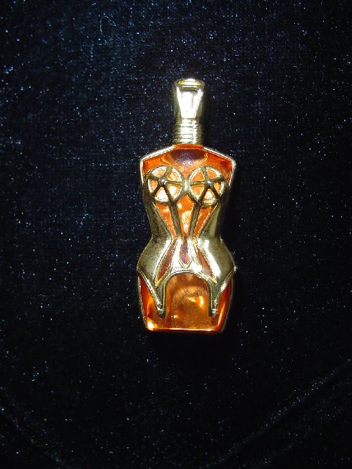 broche Gaultier avec son corset doré et l'intérieur représente le jus du parfum