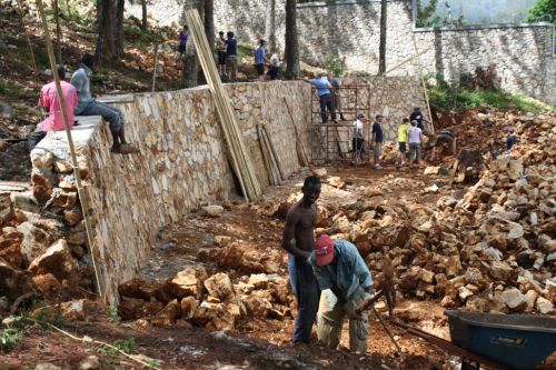 L'équipe, des jeunes adultes, travaille à enlever toutes les pierres sur le terrain des petites maisons - The team, of young adults, is working to move all the rocks from the Toddler's pods.