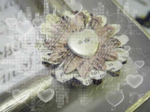 Composition de pétales de fleurs maintenue avec un bouton coeur blanc