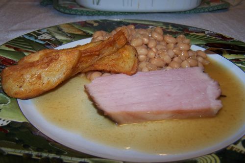 Fèves et jambonneau , à l ' assiette , accompagnés de pommes de terre frites et de crudités déjà avalées donc invisibles ! 