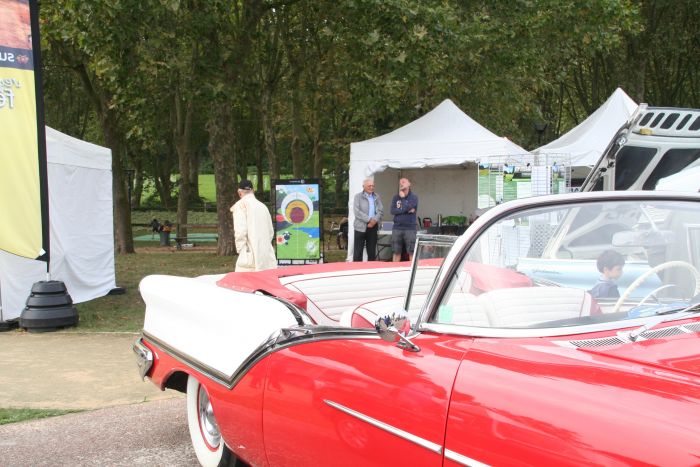 Stand de Par'tee Golf Club en arrière plan de la belle auto rouge - Rétromobile à Surenes