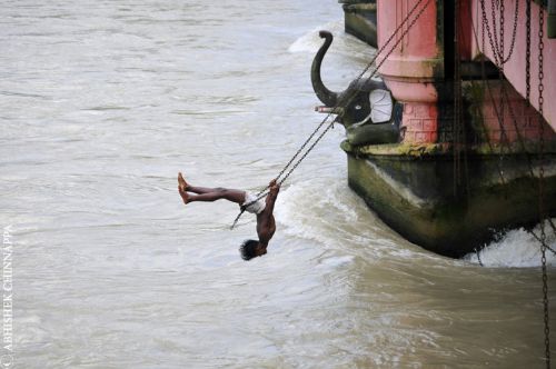 A young boy acrobatically swings from a bridge - Haridwar