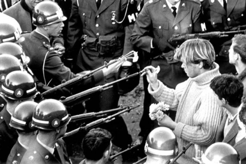 un manifestant mettant des fleurs au bout des armes des forces de lordre le 21 octobre 1967 durant la marche pour la manifestation du pentagone.jpg