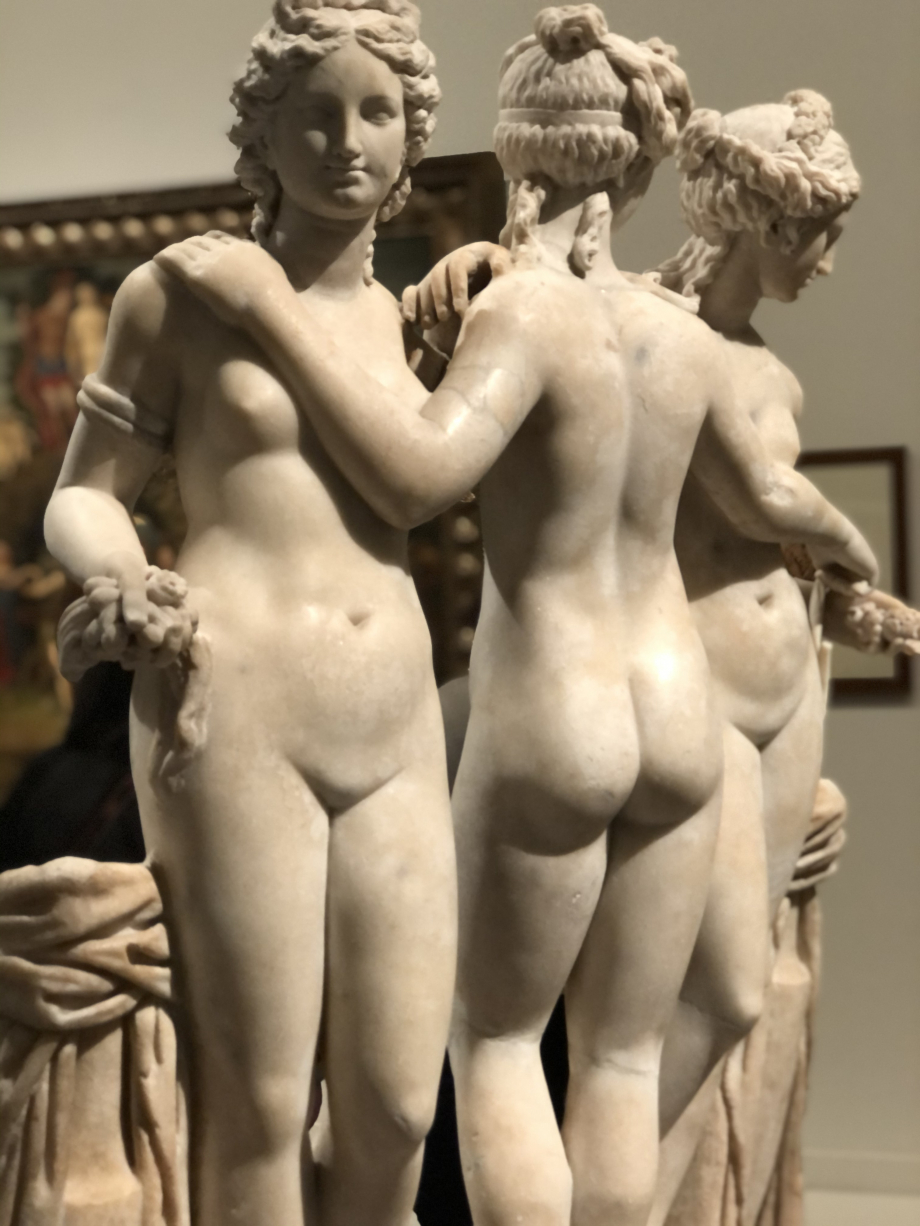 A l'origine divinités de la nature dans la mythologie grecque antique, les trois soeurs Euphrosyne, Thalie et Aglaé personnifient la beauté, les arts et la fertilité. Elles sont souvent représentées dénudées, jeunes et belles. Elles tiennent traditionnellement dans leurs mains des pommes et des roses.