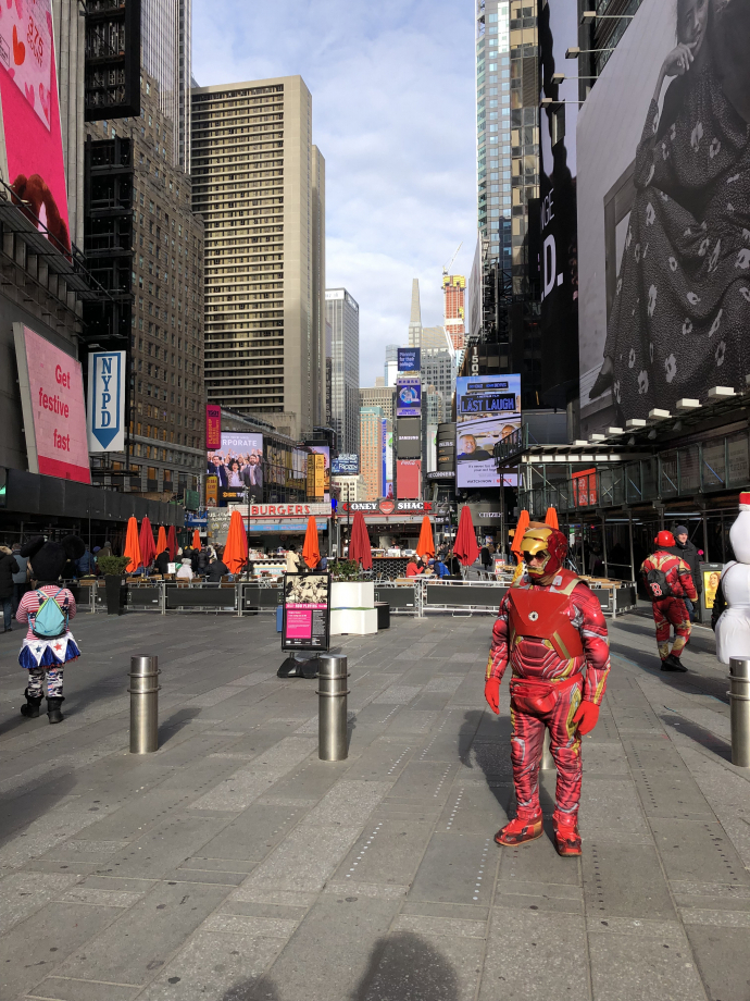 Times Square, avec des gens chelous déguisés. Et ils te harcèlent en plus ! Mais non je veux pas de photo avec Iron Man ou Disney. Damn