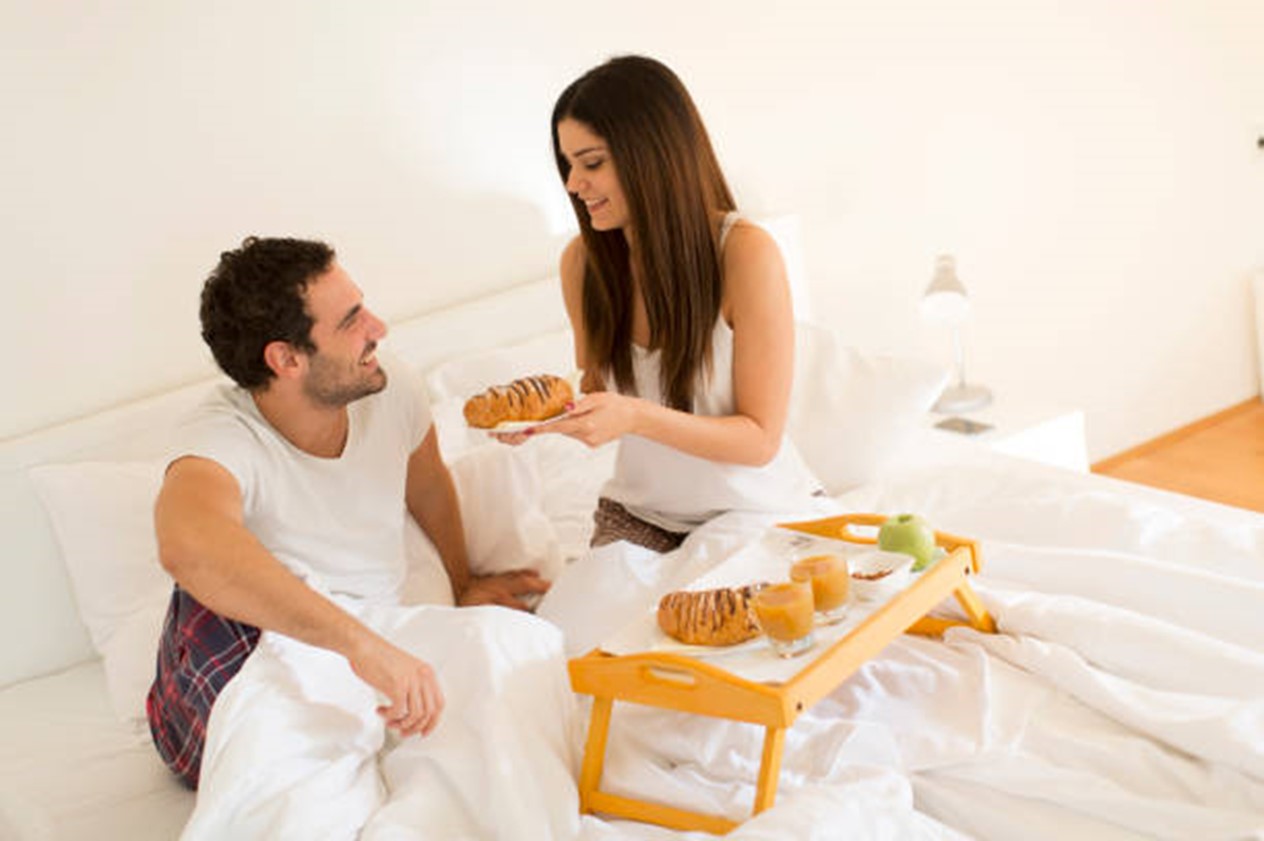 Deux amoureux qui prennent le petit déjeuner au lit