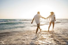 Un couple qui se tient par la main en se baladant sur la plage
