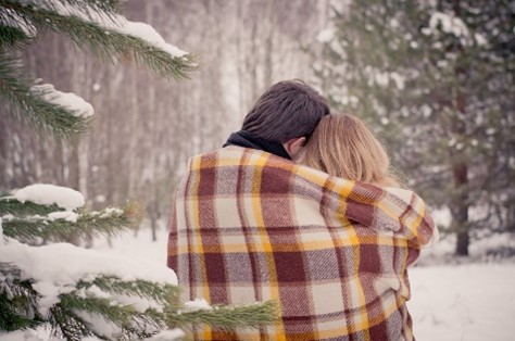 Un couple blotti sous une couverture dans la neige