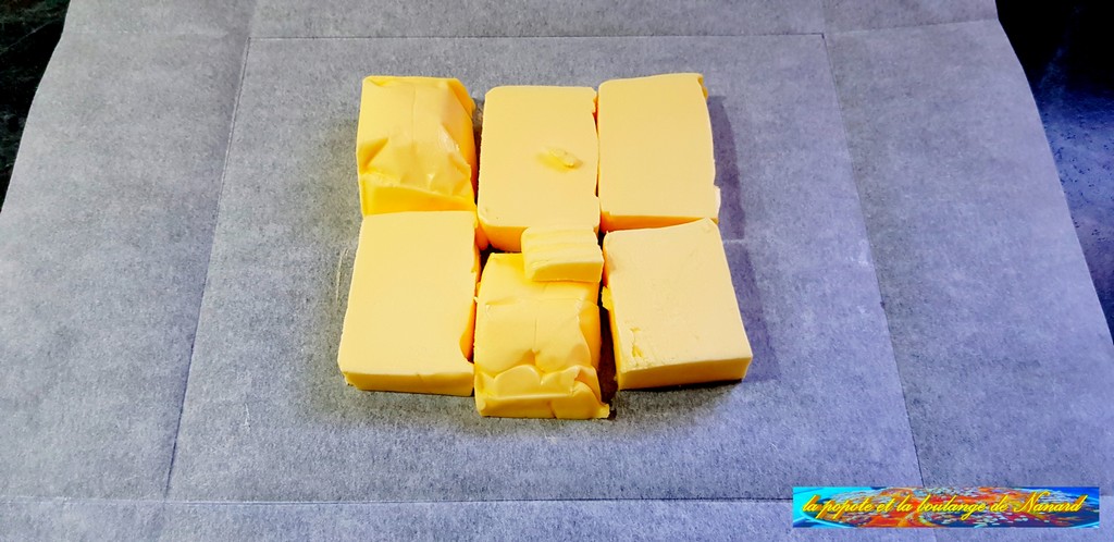 Détailler les 300 gr de beurre en six morceaux puis le déposer sur le papier