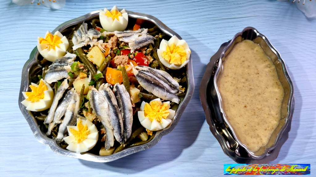 Dresser la salade dans un grand plat avec les anchois et les œufs sur le dessus