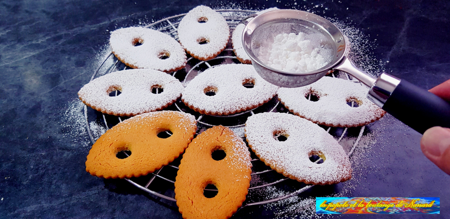 Saupoudrer généreusement de sucre glace les biscuits troués sur une grille