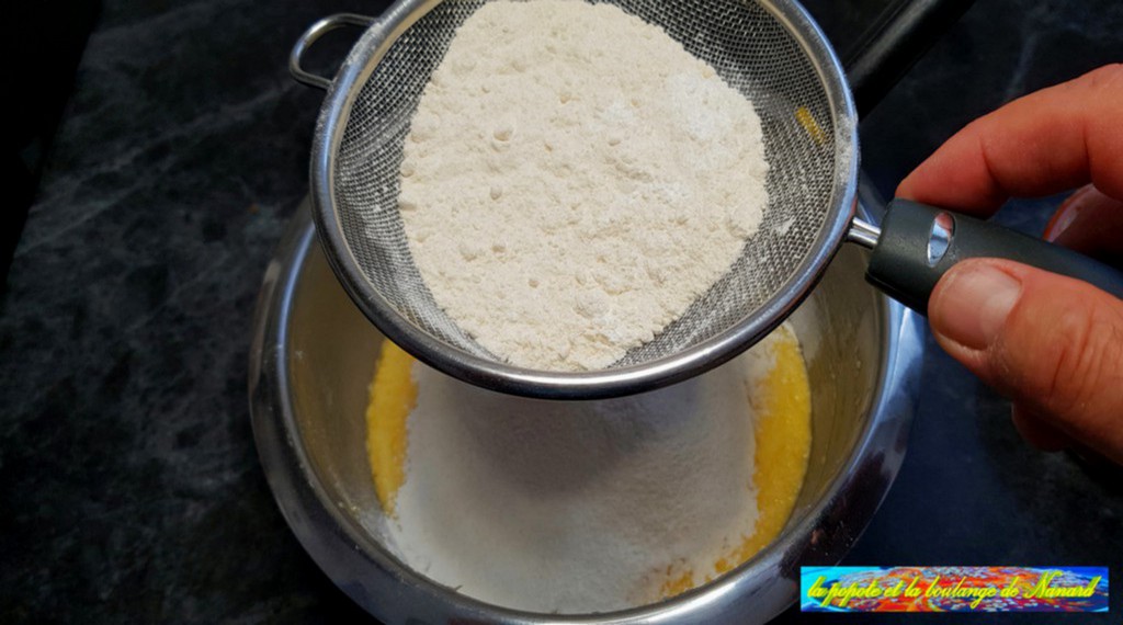 Tamiser la farine avec la levure sur le mélange beurre et œufs