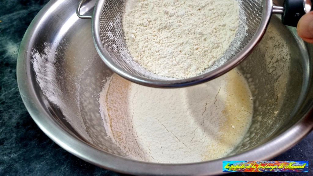 Tamiser la farine avec la levure sur le mélange œufs et sucre blanchis
