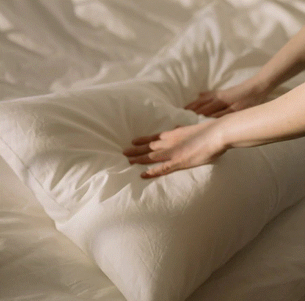 Des mains posées sur un oreiller blanc